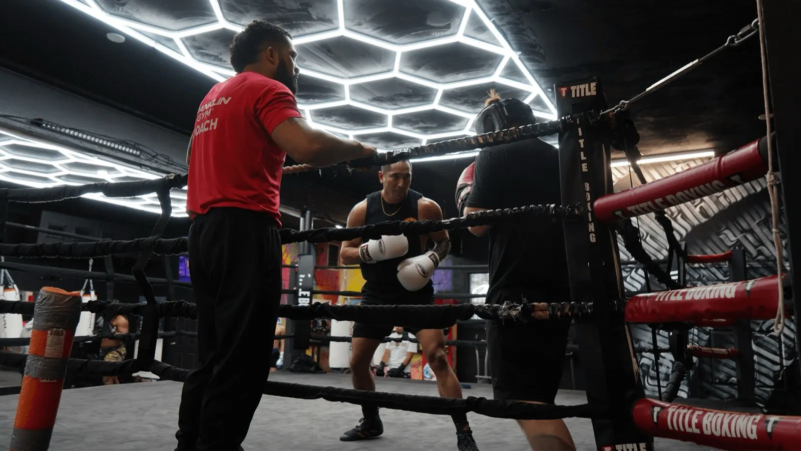 Ringside coaching — a Franklin Gym coach in the corner during sparring under the honeycomb lights